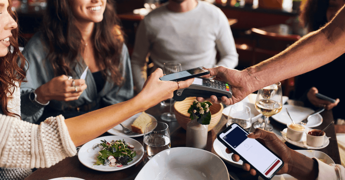 Three people at the cashier paying with a QR code, showcasing a digital quick-service restaurant (QSR) experience.